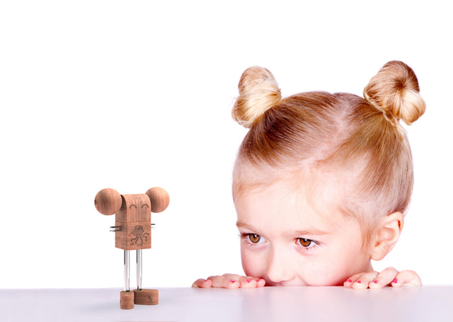 Pige med har sat op som spacebuns kigger på en traefigur fra WoodMee®